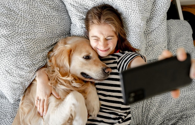 Meisje met golden retrieverhond in bed