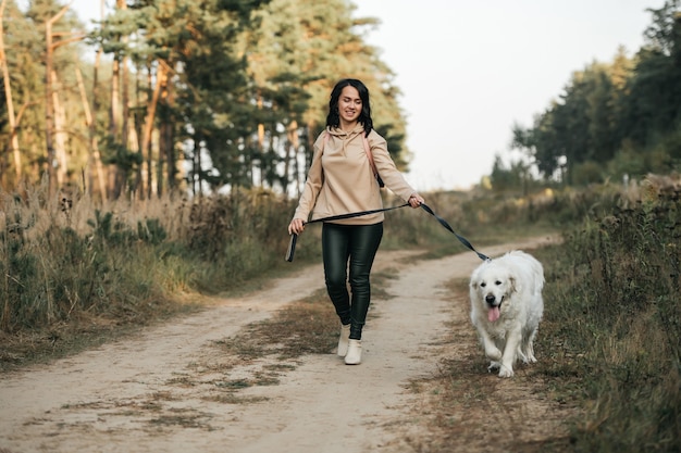Meisje met gouden retrieverhond die op bospad loopt