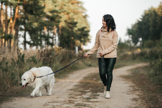 Meisje met gouden retrieverhond die op bospad loopt