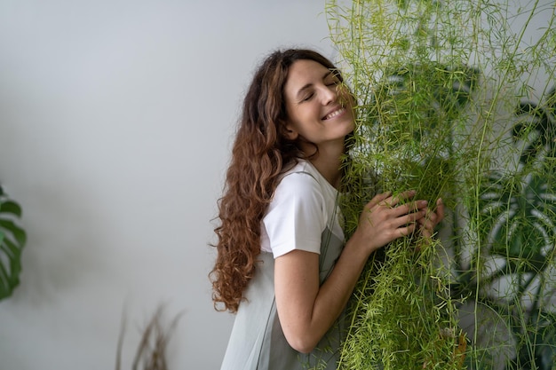 Meisje met groene bloem in haar armen met vreugde in huistuin, pas op en hou van kamerplanten