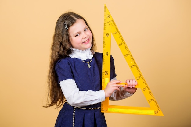 Meisje met grote liniaal Schoolstudent studie geometrie Maatvoering en meten Kid schooluniform houd liniaal Schoolonderwijsconcept Leer wiskunde Stellingen en axioma's Slim en slim concept