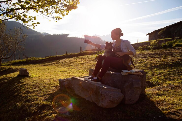 Meisje met haar hond bodeguero in het licht van de zonsondergang met de zon tegen het licht een foto maken met haar mobiele telefoon in een landelijk gebied vakantietijd herinneringen aan geluk