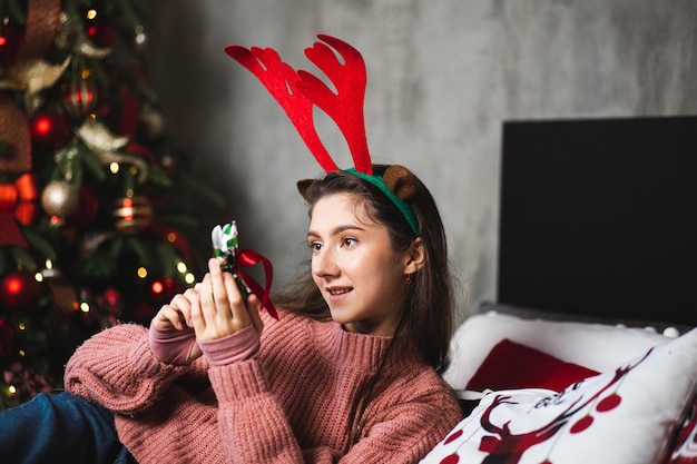 Meisje met hertengewei op de achtergrond van de kerstboom.