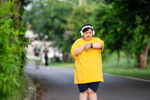 Meisje met het syndroom van Down of autisme kijkt naar de tijd terwijl ze buiten in het park loopt