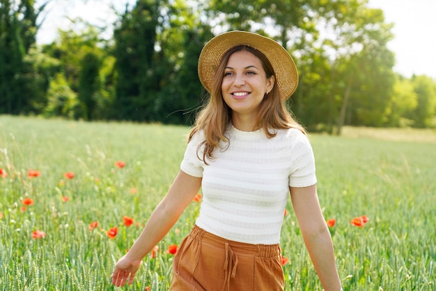 Meisje met hoed wandelen in een veld met rode bloemen. Zomer landschap. Warme kleuren. Vrouw loopt door een papaverveld. Jong meisje in de lente bloementuin.