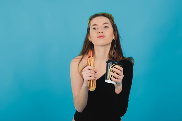 meisje met hotdog en glas met koffie op blauwe achtergrond