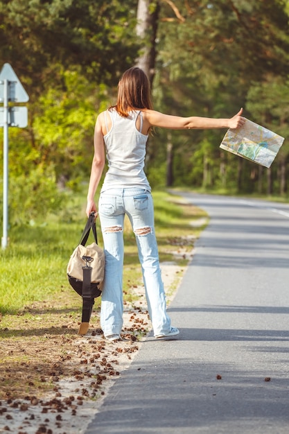 Meisje met kaart en tas in de hand lopen langs de weg