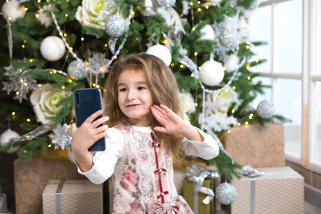 Meisje met kerstboom maakt foto's van zichzelf met smartphone