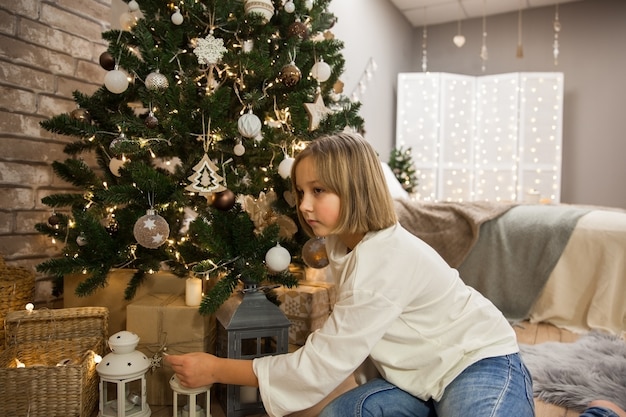 Meisje met kerstcadeautjes bij de kerstboom