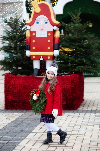 Meisje met kerstkrans op straat