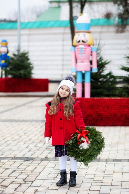 Meisje met kerstkrans op straat