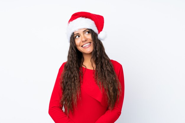 Meisje met Kerstmishoed over geïsoleerd en wit dat omhoog lacht kijkt