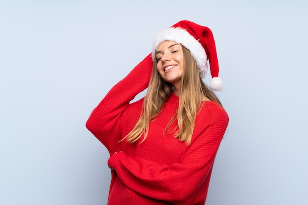 Meisje met Kerstmishoed over het geïsoleerde blauwe muur lachen