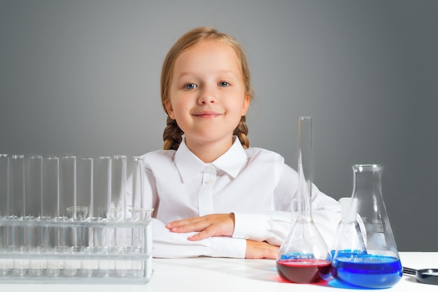 Meisje met kolven voor chemie zit aan een tafel.