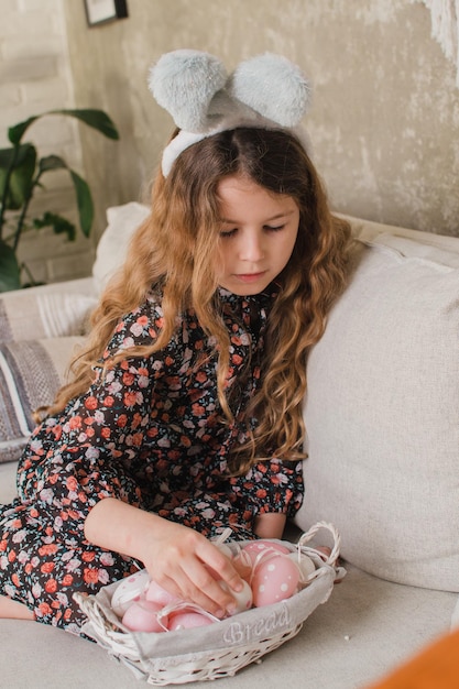 Meisje met konijnenoren die eieren in een mand leggen