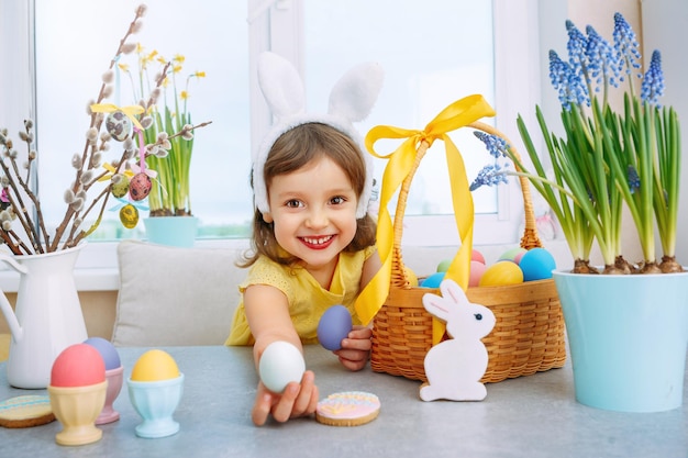 Meisje met konijnenoren op Goedemorgen aan tafel met paaseierenmand Kinderen vieren vakantie