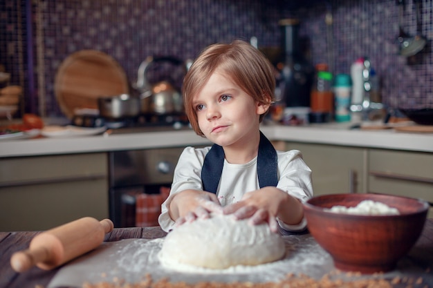 Meisje met kort haar kneden van deeg in de keuken