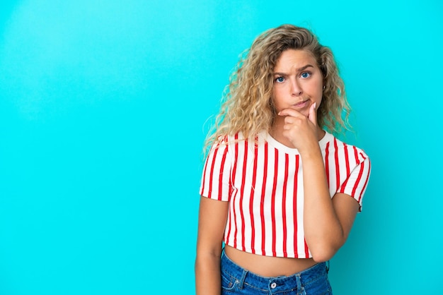 Meisje met krullend haar geïsoleerd op blauwe achtergrond met twijfels