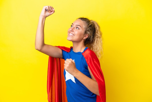 Meisje met krullend haar geïsoleerd op gele achtergrond in superheld kostuum en het vieren van een overwinning