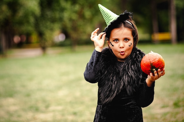 Meisje met krullend haar in een heksenkostuum voor Halloween