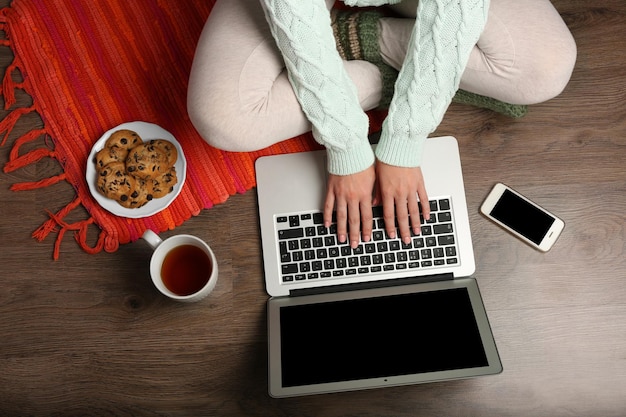 Meisje met laptop en eten ontspannen op de vloer