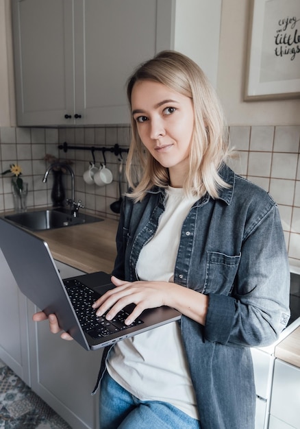 Meisje met laptop werkt in de keuken. Onderwijs op afstand vanuit huis