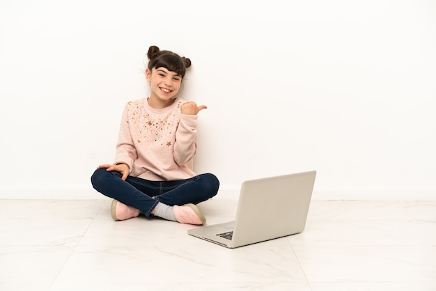 Meisje met laptop zittend op de vloer wijzend naar de zijkant om een product te presenteren