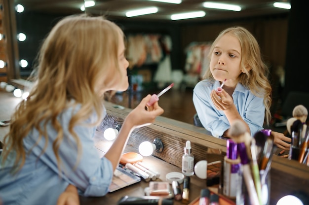 Meisje met lippenstift bij de spiegel in make-up salon