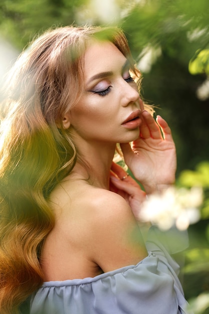 Meisje met make-up en kapsel in een bloeiende tuin close-up