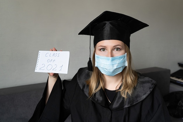 Meisje met medisch masker met afstudeerhoed met een klas van eenentwintig notitieboekje