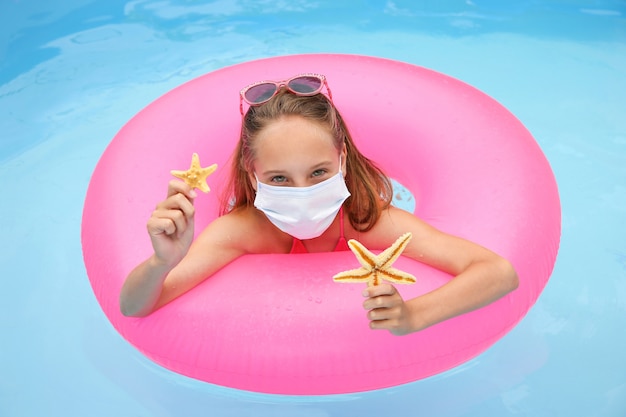 Meisje met medische masker op haar gezicht in zwembad.
