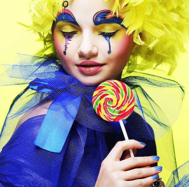 Meisje met met creatieve make-up houdt lolly