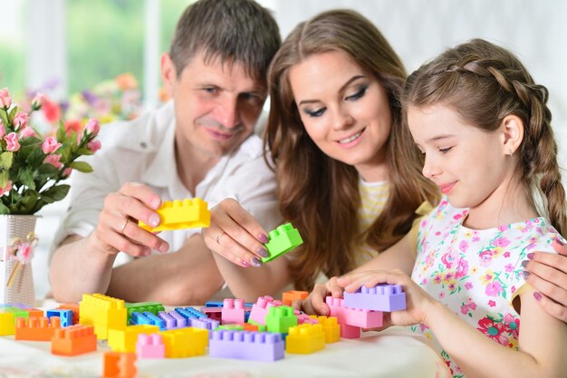 Meisje met moeder en vader spelen met kleurrijke plastic blokken