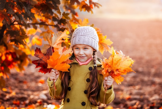 Meisje met oranje herfst esdoorn bladeren in haar handen