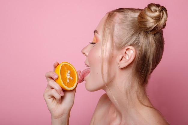 Meisje met oranje zomer op roze muur