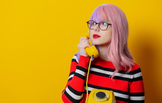 Meisje met paars haar en rode trui houdt telefoon vast op gele achtergrond