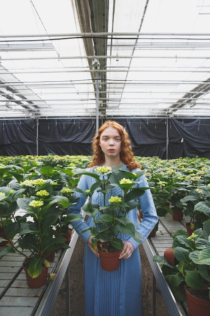 Meisje met plant in oranjerie