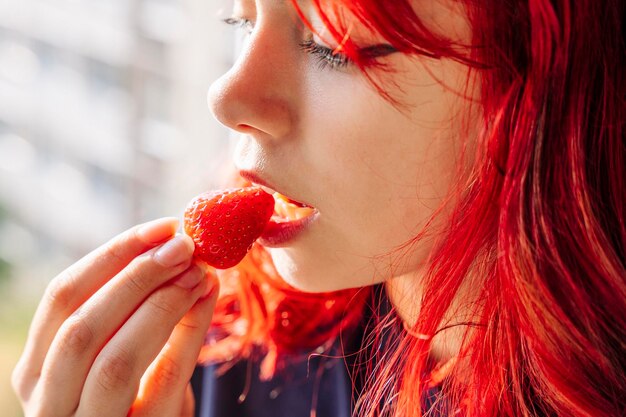 Meisje met rood haar eet heerlijke rijpe aardbeien