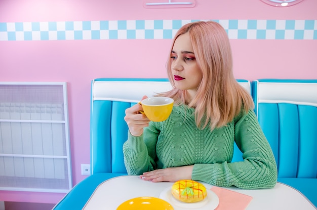Meisje met roze haren het drinken van thee in een café