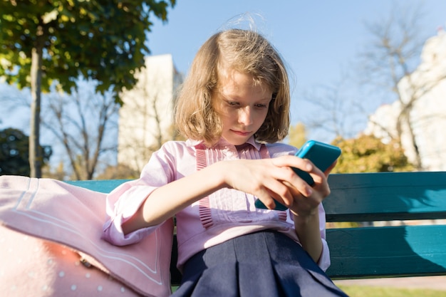 Meisje met rugzak en mobiele telefoon zittend op de bank