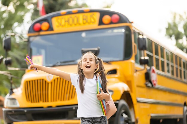 Meisje met rugzak in de buurt van gele schoolbus. vervoer voor studenten