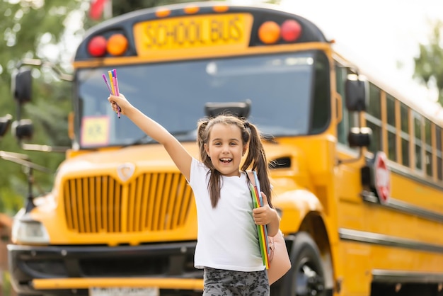 Meisje met rugzak in de buurt van gele schoolbus. Vervoer voor studenten