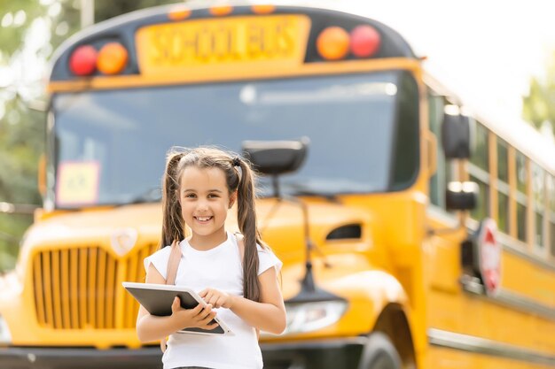 Meisje met rugzak in de buurt van gele schoolbus. Vervoer voor studenten