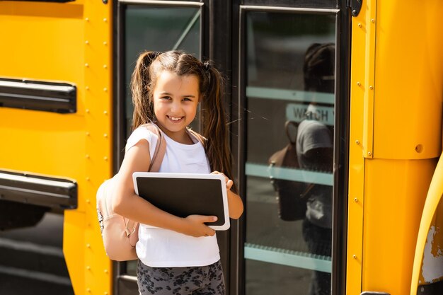 Meisje met rugzak in de buurt van gele schoolbus. Vervoer voor studenten