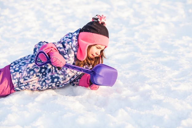 Meisje met schop lag in de sneeuw