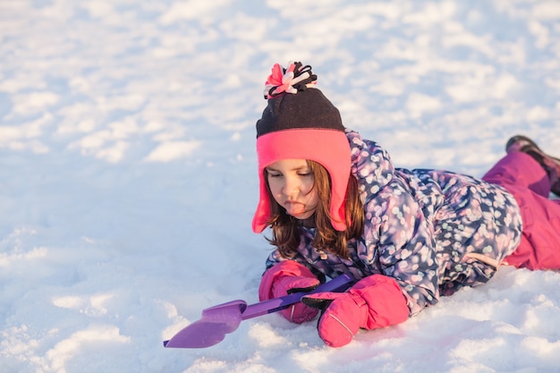 Meisje met schop lag in de sneeuw