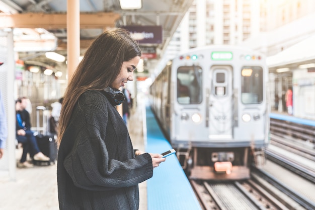 Meisje met slimme telefoon bij station in Chicago