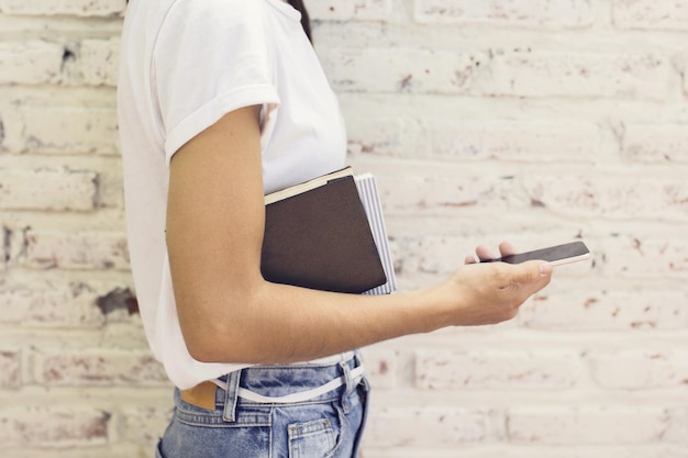 Meisje met smartphone en agenda en bakstenen muur