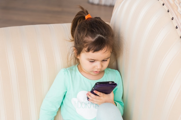 Meisje met smartphone liggend in een bed, bedtijd