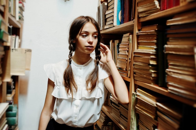 Meisje met staartjes in witte blouse bij oude bibliotheek